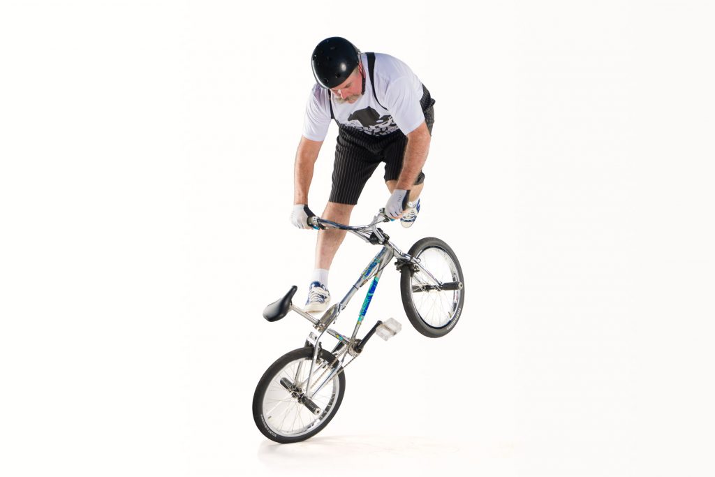 Image of Scott jumping around the front of the bike whilst it is balanced on the back wheel